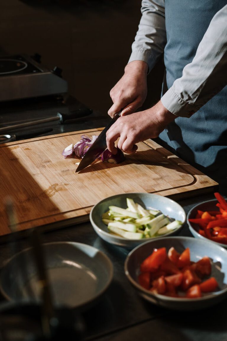 person slicing vegetable on chopping board